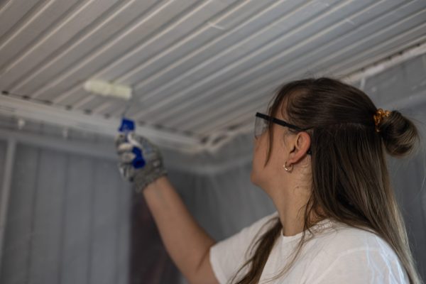 Nainen maalaa paneelikattoa telalla.